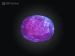 12.95 ct oval cut blue sapphire gemstone from Madagascar showing pink fluorescence under UV light