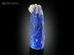 Blue afghanite crystal coated with lazurite and accented by pyrite, showing intense orange fluorescence under UV light.