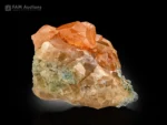 Cluster of lustrous honey-orange hessonite garnet crystals with sharp faces and delicate green mica associations from Pakistan.