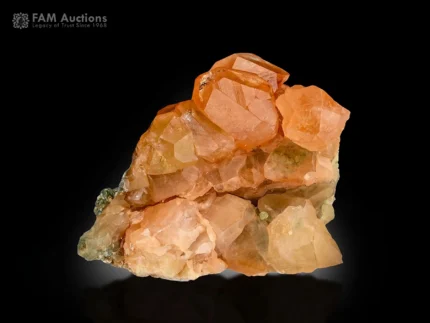 Cluster of lustrous honey-orange hessonite garnet crystals with sharp faces and delicate green mica associations from Pakistan.